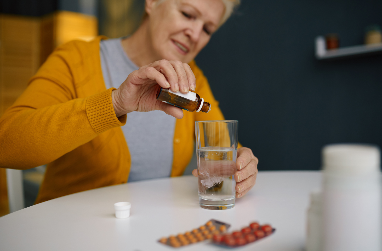 Bitterstoff, Tropfen,Frau,Glas,Wasser,Tabletten,Tisch,mit Kapseln